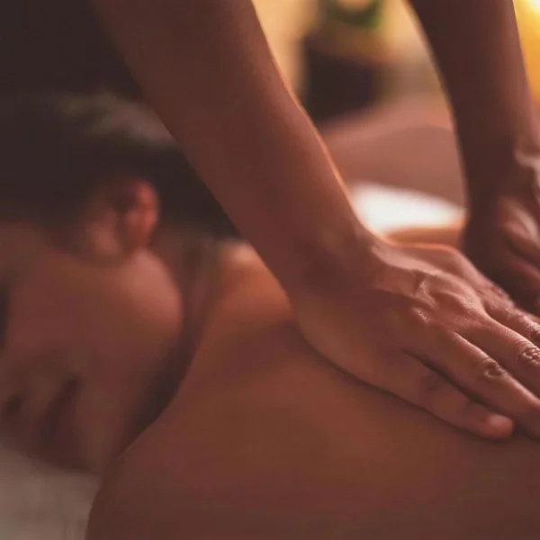 Massage relaxant du dos aux mains huilées, lumière de bougie