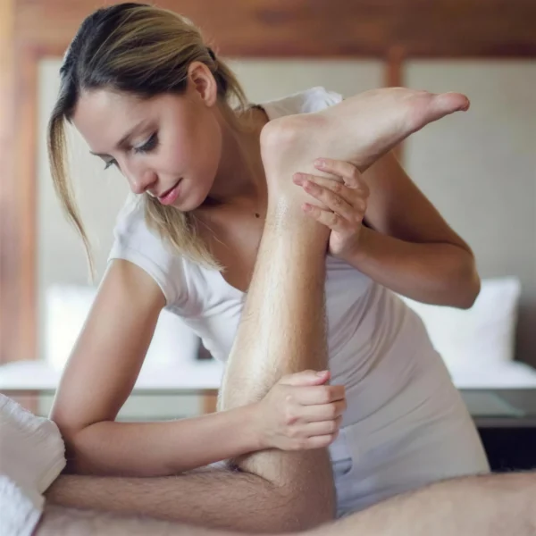 Praticienne mobilisant la jambe d’un sportif pendant un massage